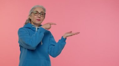 Olgun büyükanne işaret ediyor ve boş yeri gösteriyor. Ticari metinler için reklam alanı.