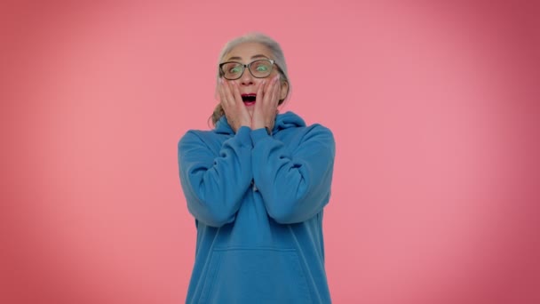 Spännande förvånad äldre kvinna höja händerna i överraskning tittar på kameran, chockad av plötslig seger — Stockvideo