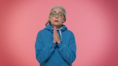 Olgun yaşlı bir kadın Tanrı 'ya dua ediyor. Dilek diliyor. Umut dolu bir ifadeyle, özür diliyor.