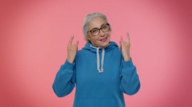 Coşkulu çılgın yaşlı kadın rock 'n roll jesti yapıyor, havalı bir işaret, dans ediyor.