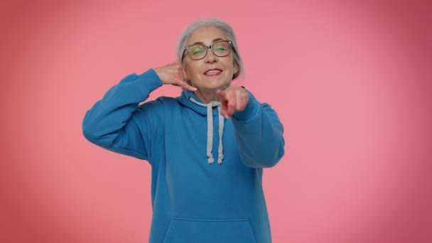 Anciana abuela mujer de pelo gris mirando a la cámara haciendo el gesto del teléfono como decir hey me llamas de nuevo — Vídeo de stock