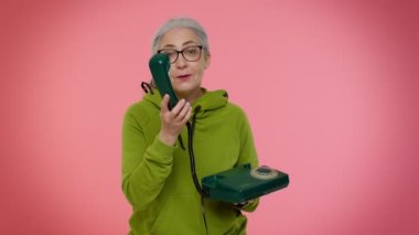 Yaşlı beyaz saçlı kadın 80 'lerin telli vintage telefonundan konuşuyor, hey beni geri ara diyor.