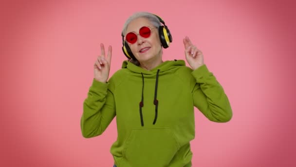 Senior woman listening music on headphones dancing disco fooling, having fun, gesticulating hands — Stock Video