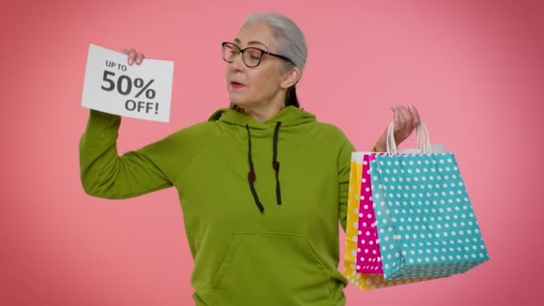 Femme mamie senior montrant des sacs à provisions et jusqu'à 50 pour cent hors inscriptions bannière, Black Friday — Video