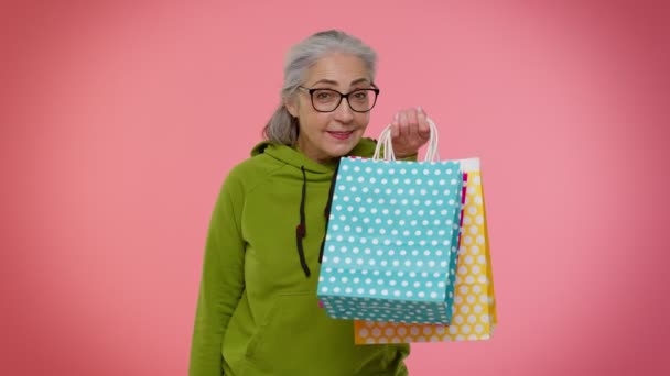 Femme mamie senior montrant des sacs à provisions et jusqu'à 70 pour cent hors inscriptions bannière, Black Friday — Video