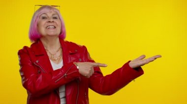 Olgun büyükanne işaret ediyor ve boş yeri gösteriyor. Ticari metinler için reklam alanı.