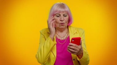 Yaşlı kadın cep telefonu kullanıyor. Ani piyango sonuçları, kötü şans, kayıp.