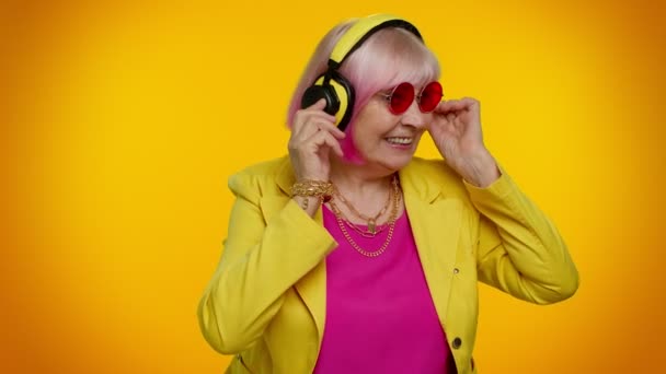 Mujer mayor escuchando música en auriculares bailando disco engañando, divirtiéndose, gesticulando manos — Vídeos de Stock