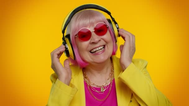 Mujer mayor escuchando música en auriculares bailando disco engañando, divirtiéndose, gesticulando manos — Vídeos de Stock