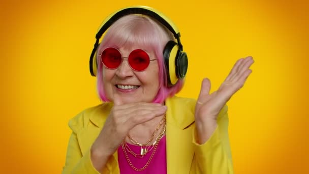 Mujer mayor escuchando música en auriculares bailando disco engañando, divirtiéndose, gesticulando manos — Vídeos de Stock
