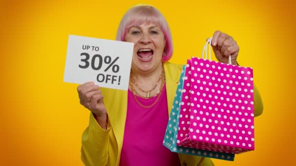 Anciana abuelita mostrando bolsas de compras y hasta 30 por ciento de descuento inscripciones texto, Viernes Negro — Vídeos de Stock