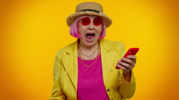 Seniorin mit Handy feiert Gewinn von Urlaubstickets — Stockvideo