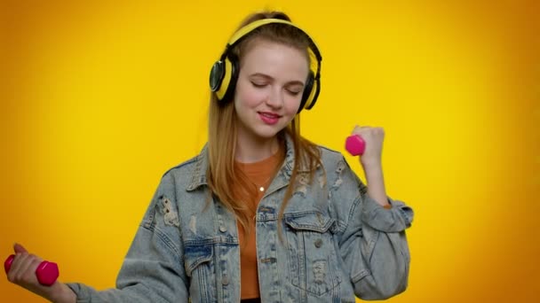 Sportowy nastolatek student dziewczyna słuchanie muzyki przez słuchawki, ćwiczenia, pompowanie hantle podnoszące — Wideo stockowe