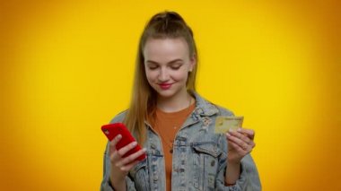 Para transfer ederken kredi kartı ve akıllı telefon kullanan genç bir kız, internetten alışveriş yapıyor.