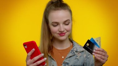 Para transfer ederken kredi kartı ve akıllı telefon kullanan genç bir kız, internetten alışveriş yapıyor.