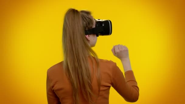 Девушка, использующая футуристическую технологию виртуальной реальности VR шлем гарнитуры, чтобы играть в симуляцию 3D видеоигры — стоковое видео
