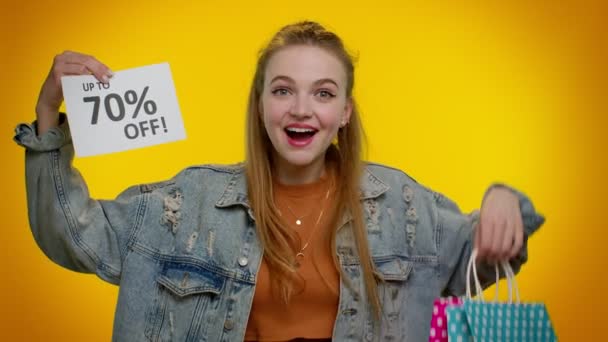 Menina adolescente alegre mostrando sacos de compras e até 70% Off banner inscrições, Black Friday — Vídeo de Stock