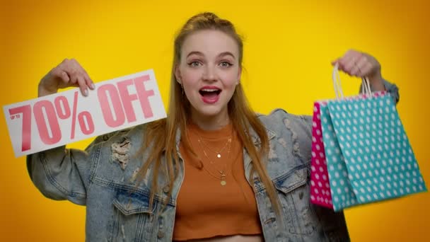 Fröhliches Teenie-Mädchen zeigt Einkaufstüten und bis zu 70 Prozent Rabatt auf Aufschriften Banner, Black Friday — Stockvideo