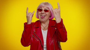 Coşkulu çılgın yaşlı kadın rock 'n roll jesti yapıyor, havalı bir işaret, dans ediyor.