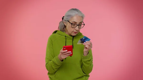 Senior old granny woman using credit plastic cards and mobile phone purchases online shopping — Stock Photo, Image