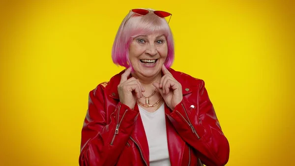 Alegre elegante anciano abuela mujer con pelo rosa en chaqueta de cuero rojo sonriendo, mirando a la cámara — Foto de Stock