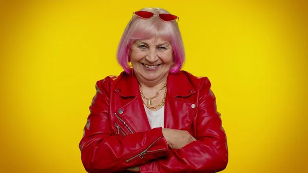 Joyeux élégant senior mamie femme avec des cheveux roses en cuir rouge veste souriant, regardant la caméra — Photo