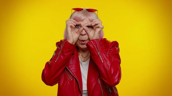 Nosy curious senior granny woman closing eyes with hand, spying through fingers, hiding, peeping