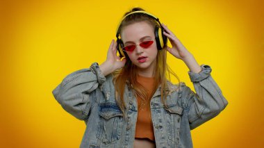 Neşeli çekici kız kulaklıkla müzik dinliyor ve dans edip eğleniyor.