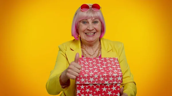 Fröhliche Seniorin öffnet Geschenkbox und lächelt fröhlich, zufrieden mit netten Geschenk — Stockfoto