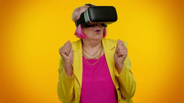 Yaşlı şık büyükanne, sanal gerçeklik VR oyunu oynamak için kulaklık uygulaması kullanıyor.