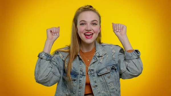 Chica adolescente en chaqueta de mezclilla gritando, levantando los puños en gesto lo hice, celebrando el éxito, ganando —  Fotos de Stock