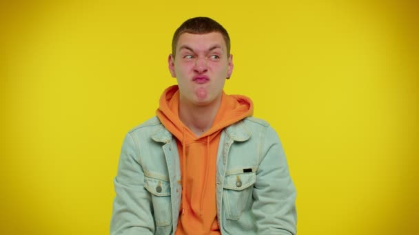 Divertido adolescente hombre haciendo juguetonas expresiones faciales tontas y muecas, jugando alrededor mostrando la lengua — Vídeo de stock