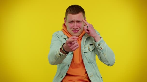 Підліток в куртці вказує на камеру і показує дурний жест звинувачує якогось ідіота в божевільному плані — стокове відео