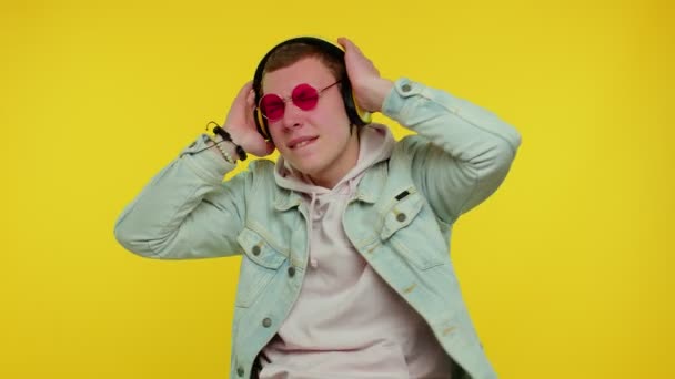 Cheerful attractive man listening music via headphones and dancing disco fooling around having fun — Stock Video