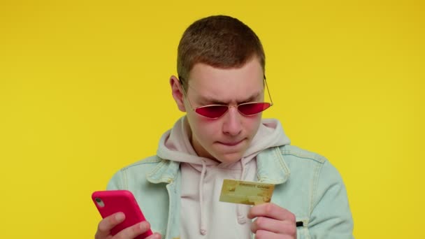 Tini férfi hitelkártyával és okostelefonnal, miközben pénzt utalnak át, vásárol online vásárlás — Stock videók