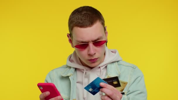 Hombre adolescente usando tarjetas bancarias de crédito y teléfono inteligente durante la transferencia de dinero, compras en línea — Vídeos de Stock
