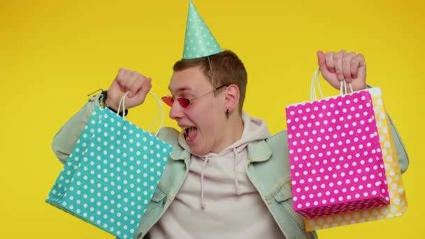 Teenie-Mann zeigt Einkaufstüten, Werberabatte, niedrige Preise, Einkaufen am Black Friday — Stockvideo