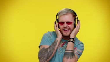 Neşeli çekici adam kulaklıkla müzik dinliyor ve dans edip eğleniyor.