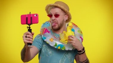 Güneş gözlüklü bir gezgin cep telefonuyla selfie çekiyor, internetten video görüşmesi yapıyor.