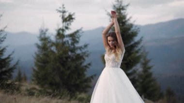 Dağın yamacında damadı bekleyen beyaz gelinlik içinde güzel, şık bir gelin.