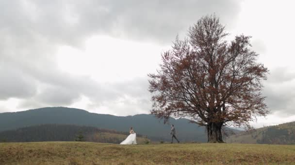 Mooi pasgetrouwde bruid bruidegom dansen op de berg herfst helling in slow motion, bruiloft paar familie — Stockvideo