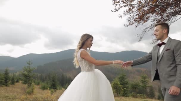 Schöne frisch vermählte Brautleute tanzen in Zeitlupe auf dem Berghang im Herbst, Hochzeitspaar Familie — Stockvideo