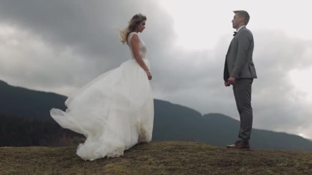 Giovani sposi sposo rimanere sul pendio della montagna, fare un bacio, coppia di sposi famiglia innamorata — Video Stock