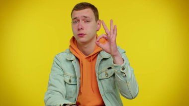 Genç stil sahibi bir adam kameraya olumlu bakıyor. İyi bir işaret veriyor gibi.