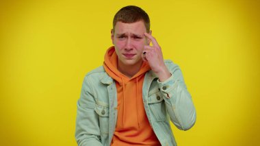 Ceketli genç bir adam kamerayı işaret ediyor ve aptalca bir hareket yapıyor. Aptalca bir plan için bir aptalı suçluyor.