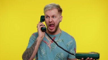 Çılgın, samimi, genç bir adam 80 'lerin klasik telefonundan konuşuyor, aptal aptal, komik suratlar yapıyor.