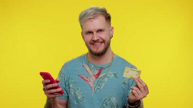 Kredi kartı ve akıllı telefon kullanan bir turist online alışverişleri aktarırken,