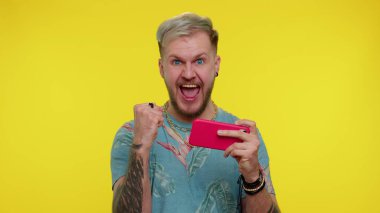 Endişeli komik bağımlı turist hevesle cep telefonuyla yarış oyunları oynuyor.