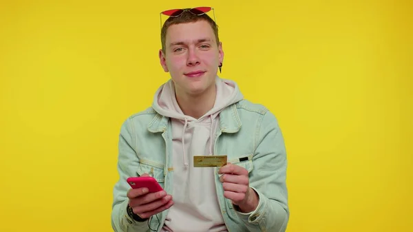 Teener Mann nutzt Kreditkarte und Smartphone beim Geldtransfer, kauft online ein — Stockfoto