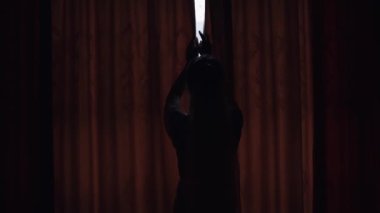 Beyaz elbiseli gelin pencerenin yanında kal ve perdeleri aç, gecelikli ve peçeli kadın.